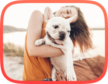 Young girl with a white french bulldog companion sitting on a beach after relaxed dog walk